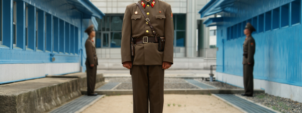 Unique View From North Korean Side: North Korean Soldiers guard the border between South and North marked by a short concrete wall. Focus on the Soldier in the Middle, Background Out of Focus.